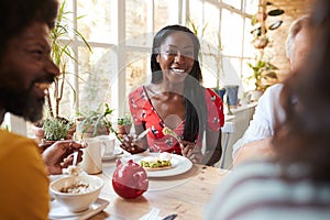 Happy young black woman eating brunch with friends at a cafe