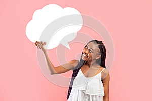 Happy young black woman holding blank speech bubble on pink studio background, mockup for design
