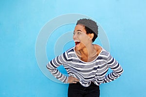 Happy young black woman laughing against blue background