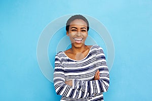 Happy young black woman laughing against blue wall