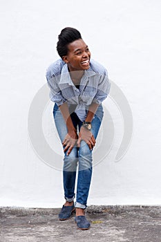 Happy young black woman laughing against white wall