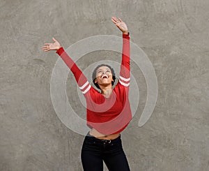 Happy young black woman laughing with arms raised