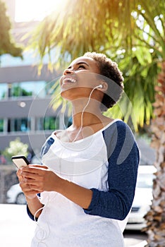 Happy young black woman listening to music on cellphone
