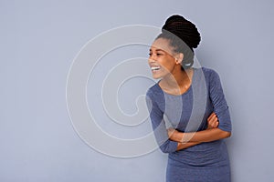 Happy young black woman looking away and smiling against gray background
