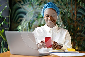 Happy young black woman managing several tasks, cafe interior