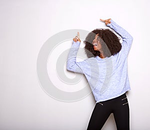 Happy young black woman pointing up and smiling against white background