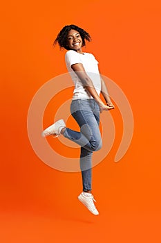 Happy young black woman posing on orange