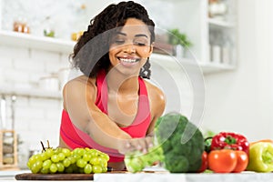 Happy young black woman preparing vegetable salad