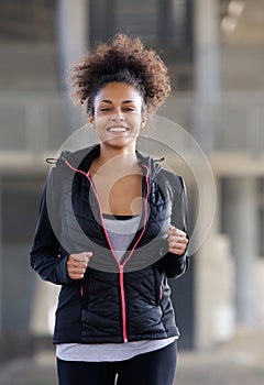 Happy young black woman running outdoors