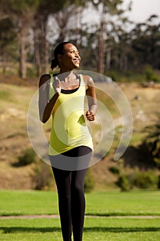 Happy young black woman running in park