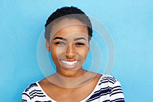 Happy young black woman smiling against blue background