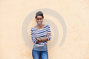 Happy young black woman smiling with arms crossed