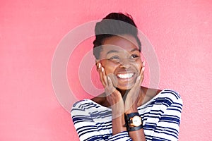 Happy young black woman smiling with hands on face