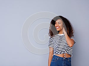 Happy young black woman smiling in striped shirt against gray background