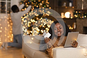 Happy young black woman with tablet, credit card enjoy online shopping, holiday sale