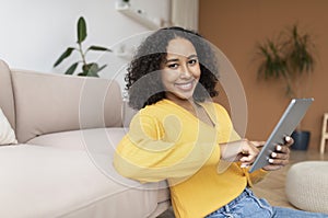 Happy young black woman with tablet pc working or studying online from home, copy space
