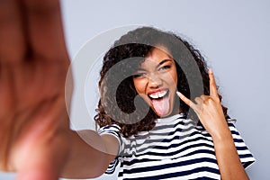 Happy young black woman taking selfie against gray wall