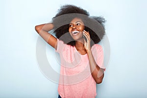 Happy young black woman talking on cellphone with hand in hair