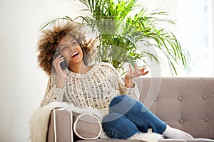 Happy young black woman talking on mobile phone at home