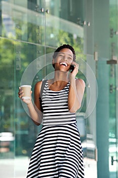 Happy young black woman walking and talking on cellphone