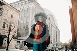 Happy young black woman is walking to the city street