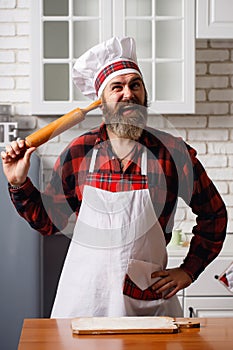 Happy young blond man in an apron in the kitchen with rolling pin in his hands, dancing having fun. Cooking Love.