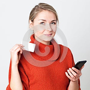 Happy young blond woman consuming on cell phone with credit card