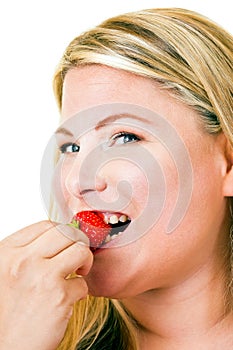 Happy young blond woman eating strawberry