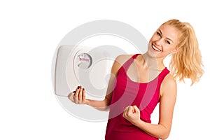 Happy young blond woman showing a scale as she has perfect shape
