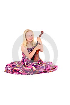 Happy young blonde girl in a wide flowery dress poses with violin on a white studio background