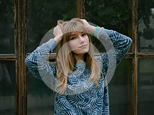 Happy young blonde woman with adorable smile enjoying early spring morning in city park posing outdoors with big window and