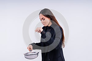 Happy young blonde woman sifts through a sieve on red white bsckground in studio