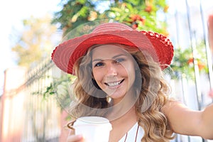 Happy young blonde woman smiling broadly making self portrait on her device outdoor