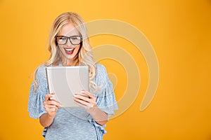 Happy young blonde woman using tablet computer.