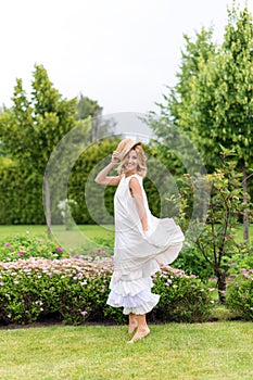 Happy young blonde woman walking barefoot on the green grass