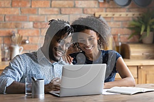 Happy young bonding african american family couple using computer.