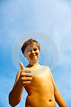 Happy young boy at the beach with thumbs up