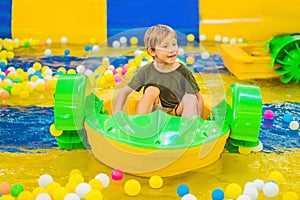 Happy young boy on the boat enjoying playing on amusement park