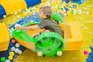 Happy young boy on the boat enjoying playing on amusement park