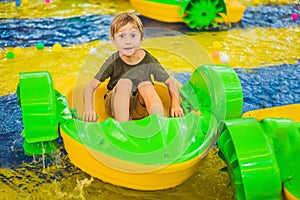 Happy young boy on the boat enjoying playing on amusement park