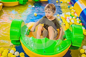 Happy young boy on the boat enjoying playing on amusement park