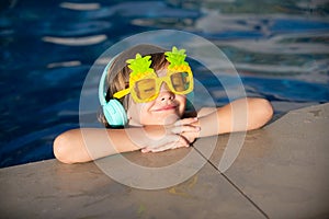 Happy young boy child having fun in the water and enjoys summer vacation in the pool. Happy carefree childhood concept.