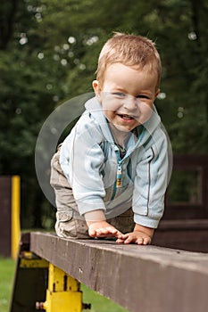 Happy young boy crawling on the ladder