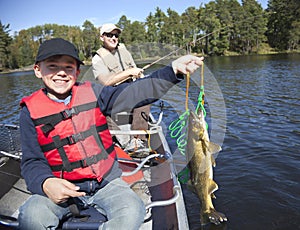 Happy young boy fisherman holds up a stringer of nice walleyes