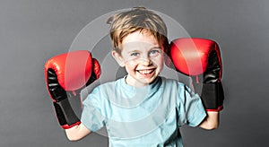 Happy young boy with freckles holding big boxing gloves