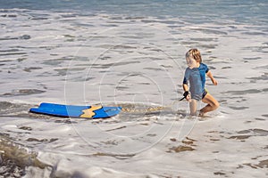 Happy Young boy having fun at the beach on vacation, with Boogie board