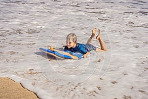 Happy Young boy having fun at the beach on vacation, with Boogie board