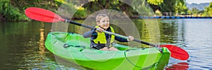 Happy young boy holding paddle in a kayak on the river, enjoying a lovely summer day BANNER, LONG FORMAT