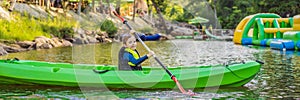 Happy young boy holding paddle in a kayak on the river, enjoying a lovely summer day BANNER, LONG FORMAT