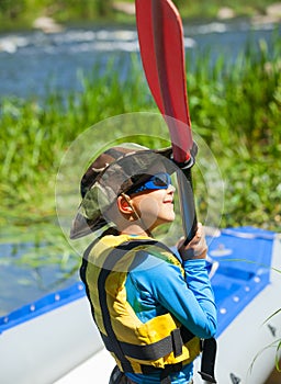 Happy young boy holding paddle near a kayak